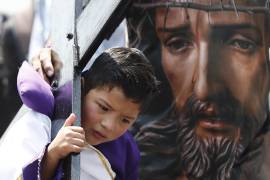Un niño vestido de nazareno carga una cruz durante la representación numero 182 de la pasión de Cristo este viernes, en la alcaldía de Iztapalapa, en la Ciudad de México (México).