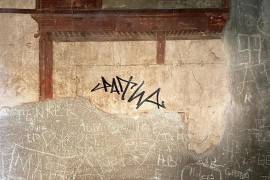 Turista vandaliza una pared con frescos en una antigua ciudad de Italia