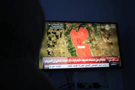 Una persona observa una TV que muestra la ubicación de una instalación de almacenamiento de petróleo en Saná, Yemen.