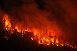 Un helicóptero que realiza operaciones nocturnas se prepara para arrojar agua sobre el incendio forestal de Quilpituk Creek, en la orilla occidental del lago Okanagan cerca de Fintry, Columbia Británica, Canadá.
