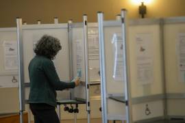 Wendy Fiering, una voluntaria, cuelga un recordatorio en las cabinas de votación para llenar ambos lados de la boleta mientras la gente se reúne en el lugar de votación en la Legión Americana en Brattleboro, Vermont.