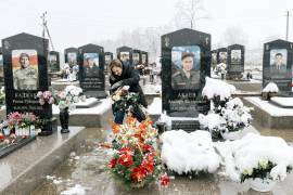 Oksana Abaeva retira la nieve de las flores en la tumba de su hijo, Albert Abaev, en Vladikavkaz, la capital de la región rusa de Osetia del Norte, el 28 de febrero de 2026.
