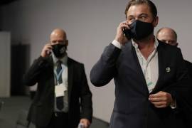 El actor estadounidense Leonardo Di Caprio, en el centro, habla por un teléfono móvil mientras camina por el pasillo durante la COP26 Cumbre del Clima de la ONU en Glasgow, Escocia. AP/Alastair Grant