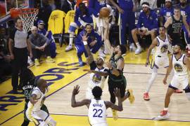 El alero de los Boston Celtics, Jayson Tatum (c), busca lanzar un tiro más allá del alero defensor de los Golden State Warriors, Juan Toscano-Anderson (c-i), durante el quinto juego de playoffs de las Finales de la NBA.