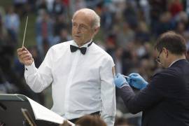 El director Ivan Fischer, fundador de la Orquesta del Festival de Budapest, recibe su tercera dosis de la vacuna contra el COVID-19 mientras dirige a la orquesta en un concierto gratuito al aire libre en Budapest, Hungría. AP/Laszlo Balogh