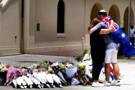 Una pareja deposita flores en un homenaje a las víctimas del tiroteo afuera del Bondi Pavilion en la playa Bondi de Sídney.