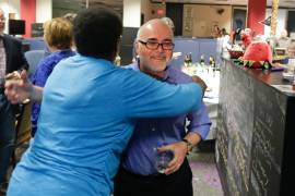 El caricaturista Kevin Siers (d) del periódico Charlotte Observer, es abrazado por una colega luego de que Siers ganó el Premio Pulitzer a la caricatura editorial, el lunes 14 de abril de 2014, en Charlotte, Carolina del Norte.