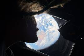 La astronauta Christina Koch, especialista de la misión Artemis II, mirando hacia la Tierra desde una de las ventanas de la cabina principal de la nave espacial Orion mientras la tripulación viaja hacia la Luna.