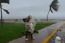 Un hombre camina a lo largo de la costa mientras los árboles son azotados por el viento en Kingston, Jamaica, el 28 de octubre de 2025.