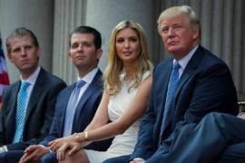 Donald Trump sentado con sus hijos, de izquierda a derecha, Eric Trump, Donald Trump Jr. e Ivanka Trump durante una ceremonia de inauguración del Trump International Hotel el 23 de julio de 2014 en Washington.
