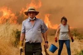 Los residentes locales reaccionan frente al fuego durante un incendio forestal en Santa Baia De Montes, noroeste de España, el jueves 14 de agosto de 2025.
