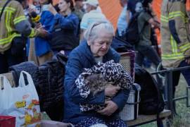 Una mujer mayor sostiene a su gato en brazos, sentada junto a sus pertenencias delante de un edificio residencial que sufrió importantes daños en un ataque nocturno ruso, en Kiev, Ucrania, el 20 de agosto de 2026.