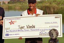 Tiger Woods posa con una copia del cheque que recibió tras ganar su primer torneo como profesional, el Las Vegas Invitational, el 6 de octubre de 1996 en Las Vegas. Ese día de hace 25 años arrancó una nueva era en el golf, con un Woods que a los 20 años hacía cosas que nadie había hecho antes. (AP Photo/Lennox McLendon, File)