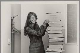 La directora de la División de Ingeniería de Software del Laboratorio de Instrumentación del MIT, Margaret Hamilton, junto a una pila de listados del software de vuelo del Apolo, desarrollado por ella y su equipo.