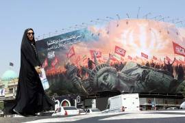 Una mujer iraní con velo pasa junto a una valla publicitaria antiamericana en la plaza Enghelab, en el centro de Teherán, Irán, el 3 de agosto de 2026.