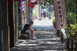 Un joven revisa su celular en una solitaria calle de la alcaldía Cuauhtémoc, Ciudad de México.