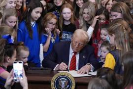 Imanen del 5 de febrero del presidente estadounidense Donald Trump (c), rodeado de jóvenes atletas, firma una orden ejecutiva que prohíbe a las atletas transgénero participar en deportes femeninos, en Washington.