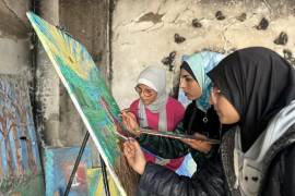 La artista visual Maisa Yusef (2d) trabaja entre los escombros de su estudio, destruido por los ataques aéreos israelíes, donde lleva a cabo talleres de arteterapia y dibujo.