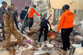 En esta fotografía difundida por la Agencia Nacional de Búsqueda y Rescate (BASARNAS) de Indonesia, equipos de rescate intentan retirar escombros de un edificio.