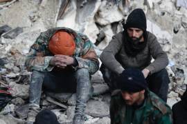 Dos personas reaccionan mientras se sientan sobre los escombros de los edificios derrumbados, en Alepo, Siria.