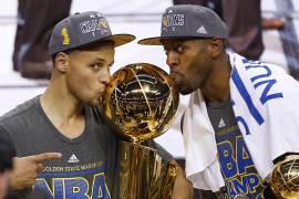 ARCHIVO.- Stephen Curry, izquierda, y Andre Iguodala, de los Warriors de Golden State besan el trofeo Larry O'Brien después de derrotar a los Cavaliers de Cleveland 105-97 en el Juego 6 de las Finales de la NBA en Cleveland, el 17 de junio de 2015.