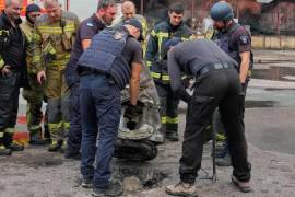 Bomberos examinan un fragmento de un misil ruso tras los ataques aéreos a un almacén de alimentos en Kiev, Ucrania, el miércoles 5 de agosto de 2026.