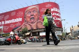 Una mujer pasa junto a un cartel anti-Estados Unidos y Trump en una calle de Teherán, Irán.
