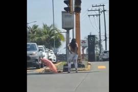 La mujer, de unos 25 años, se quita la ropa sin pudor alguno, por unos momentos parece que posa para los automovilistas detenidos por el semáforo