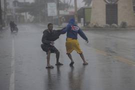 Dos jóvenes caminan con dificultad debido a los fuertes vientos durante el paso del huracán Fiona en Nagua, República Dominicana.