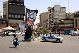 Una mujer iraní camina con sus bolsas de la compra junto a una pancarta antiamericana que muestra al presidente de Estados Unidos, Donald Trump, en el norte de Teherán, Irán, el 25 de agosto de 2026.