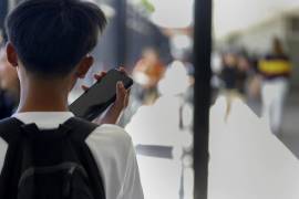 Un estudiante usa su teléfono celular después de desbloquear la funda que lo protege contra su uso durante el día escolar en Bayside Academy, en San Mateo, California.