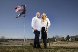 Jennifer y Tim Kohl en su jardín delantero con la bandera estadounidense y una bandera azul en Star, Idaho. La pareja se mudó recientemente a Idaho desde el área de Los Ángeles.