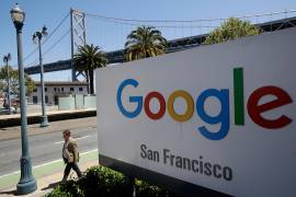 En esta foto de archivo del 1 de mayo de 2019, un hombre pasa caminando frente a un letrero de Google, con un tramo del puente de la Bahía (Bay Bridge) al fondo, en San Francisco.