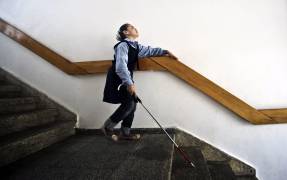 En la imagen, una niña ciega se ayuda de un bastón para bajar las escaleras.