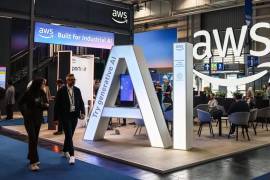 Fotografía de archivo de dos visitantes pasando junto al stand de Amazon Web Services (AWS).