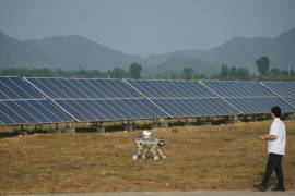 Un trabajador controla un perro robótico cerca de paneles solares en una planta de energía fotovoltaica operada por Huadian (Beijing) New Energy Development Co. Ltd. en Pekín.