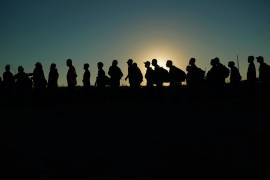 Migrantes que cruzaron el rio Bravo y entraron sin autorización a Estados Unidos desde México forman una fila para ser procesados por la Oficina de Aduanas y Protección Fronteriza en Eagle Pass, Texas.