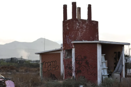 La estructura de la antigua escuela permanece abandonada mientras, a la distancia, se observa humo en el sector donde vecinos han denunciado reiteradamente la quema de llantas.