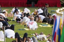 Narendra Modi, primer ministro de la India, hace yoga en un parque con personas a su alrededor.
