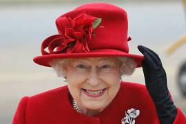 La reina Isabel II de Gran Bretaña sostiene su sombrero por los fuertes vientos al llegar a una visita al Valle RAF en Anglesey, Gales, el 1 de abril de 2011.