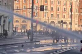 La mujer caminaba con paso firme cerca del frente de la multitud, vestida con ropa llamativa, antes de que un chorro directo de agua a alta presión la arrojara al suelo.