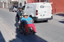 Oficiales de la Policía Turística ayudan a una mujer en silla de ruedas en el Centro Histórico de Saltillo.