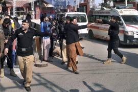 Los oficiales de policía despejan la ruta de las ambulancias que transportan heridos desde la escena en Peshawar, Pakistán