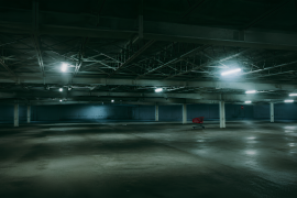 Un carrito abandonado basta para alterar el sentido de un estacionamiento vacío: la luz sigue encendida, las columnas siguen en pie, pero el lugar ya no parece esperar autos, sino algo más.