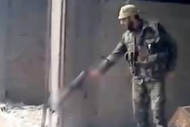 Foto del archivo de AP tomada de un video de 2013, que muestra a un soldado sirio disparando a una zanja llena de cuerpos, en el vecindario de Tadamon, en Damasco, Siria.