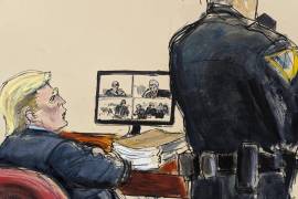 El expresidente Donald Trump sentadoa en la mesa de la defensa mientras David Pecker, que se muestra en la pantalla de video, testifica sobre Karen McDougal en el tribunal penal de Manhattan.