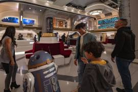 Un grupo de personas son recibidos por el droide astromecánico SK-62O en el atrio del crucero estelar Halcyon, en el hotel atracción “Star Wars: Galactic Starcruiser”. EFE/Matt Stroshane/Disney