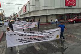 Ex trabajadores de AHMSA recorren calles de Monclova con lonas para exigir solución al conflicto laboral.