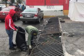 Personal retira basura, hojas y tierra que pueden obstruir las rejillas durante las lluvias.