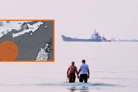 Dos hombres caminan en las aguas del estrecho de Ormuz con barcos fondeados más lejos, cerca de Bandar Abbas, Irán, el domingo 12 de julio de 2026, informó la AP.